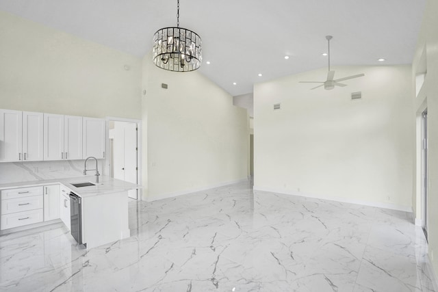 kitchen featuring white cabinets, kitchen peninsula, high vaulted ceiling, and sink