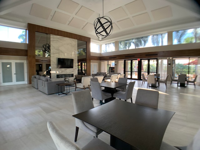 dining area with a premium fireplace, french doors, and a high ceiling