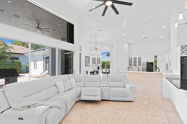 living room with a high ceiling, ceiling fan with notable chandelier, a wealth of natural light, and light tile patterned flooring