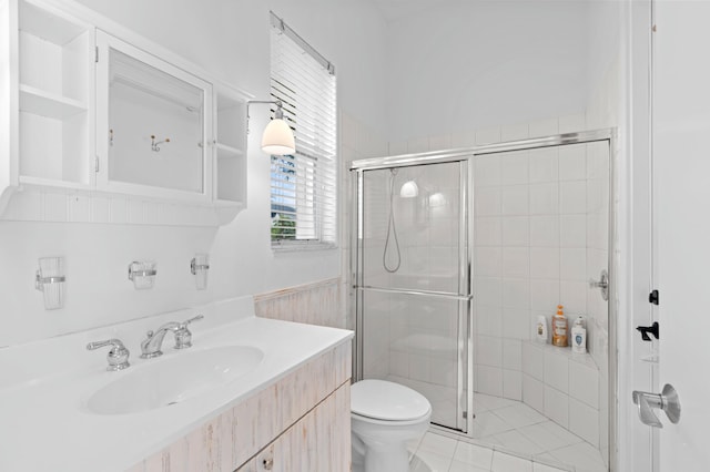 bathroom with tile patterned floors, vanity, toilet, and a shower with shower door