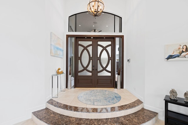 tiled entrance foyer featuring an inviting chandelier, a high ceiling, and french doors