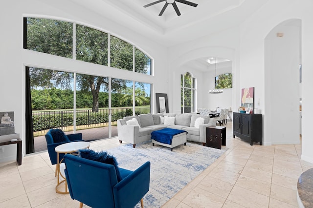 tiled living room with ceiling fan, a towering ceiling, and a tray ceiling