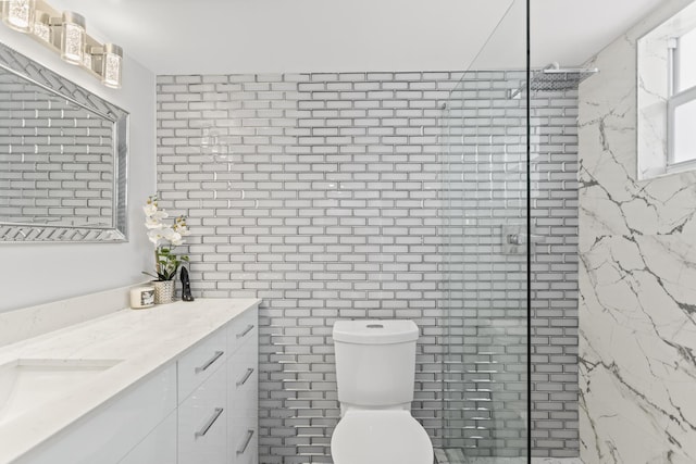 bathroom featuring a tile shower, vanity, and toilet