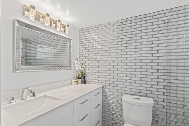 bathroom featuring vanity, toilet, and tile walls