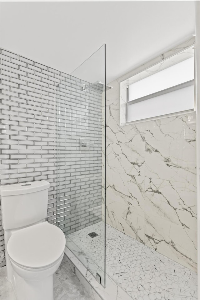 bathroom featuring tiled shower and toilet