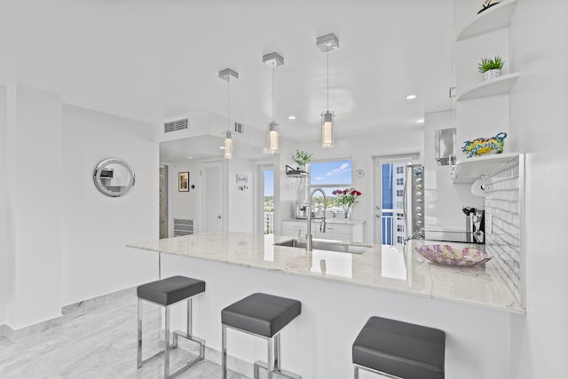 kitchen with white cabinets, light stone countertops, hanging light fixtures, and sink