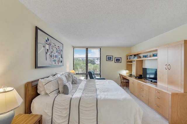 carpeted bedroom with a textured ceiling and built in desk