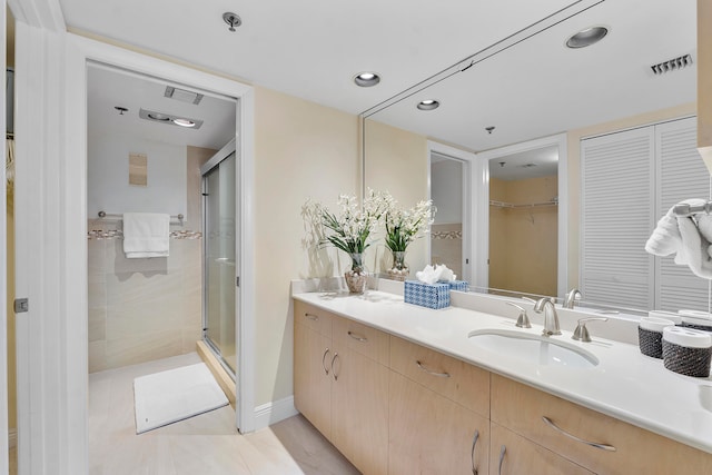 bathroom featuring a shower with door, vanity, and tile patterned floors