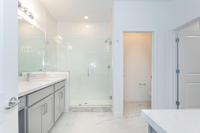 bathroom featuring vanity, a shower with shower door, and toilet