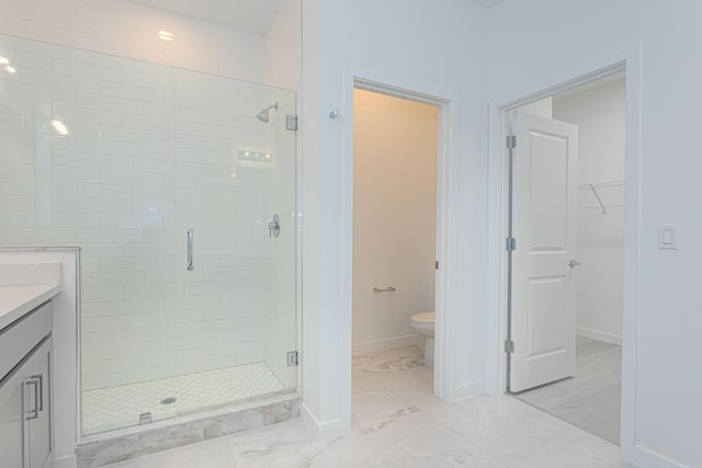 bathroom featuring vanity, toilet, and a shower with door