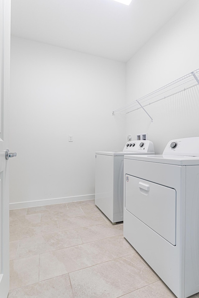 laundry room featuring washing machine and clothes dryer and light tile patterned floors