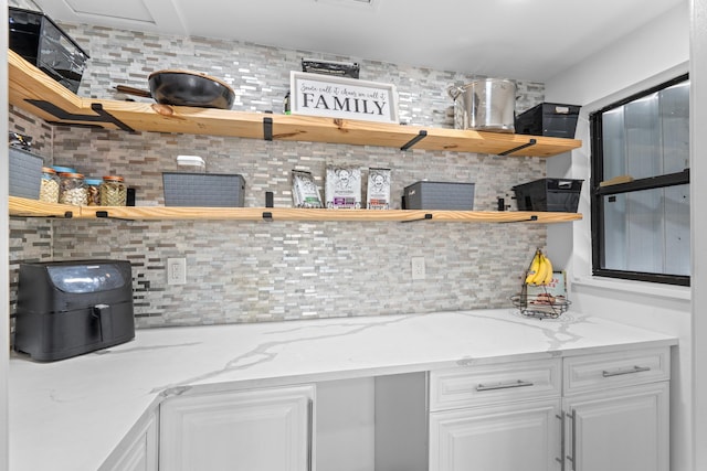 kitchen with white cabinetry, light stone counters, and tasteful backsplash