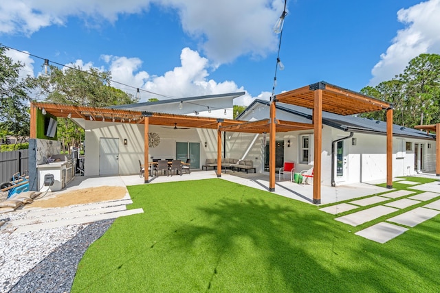 rear view of property featuring an outdoor kitchen, a yard, and a patio