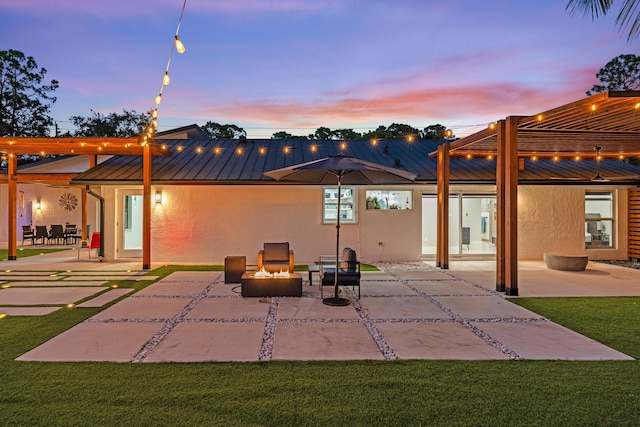 back house at dusk with a yard and a patio