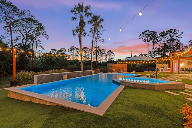 pool at dusk featuring a lawn and a patio area