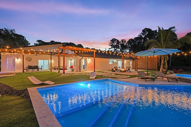 pool at dusk with a pergola, a yard, and a patio area