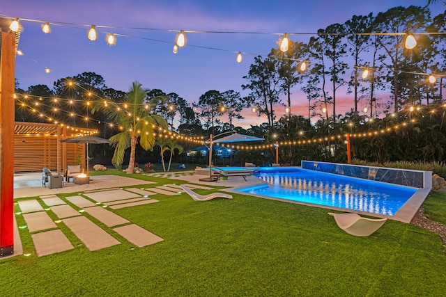 pool at dusk featuring a yard, a pergola, and a patio area