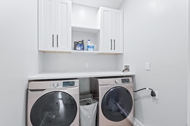 clothes washing area with cabinets and washer and clothes dryer