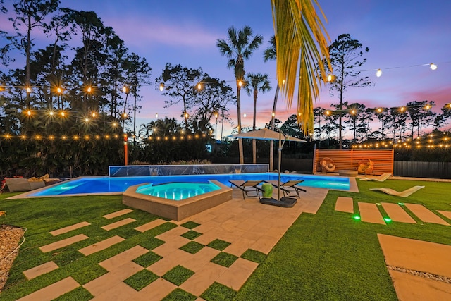 pool at dusk featuring a patio and a lawn