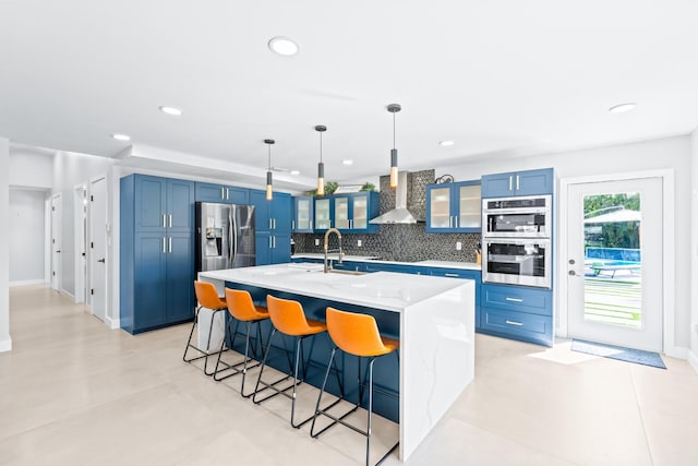 kitchen with stainless steel appliances, light stone counters, decorative backsplash, sink, and decorative light fixtures