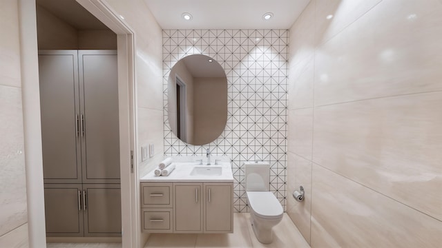 bathroom featuring toilet, vanity, and tile walls