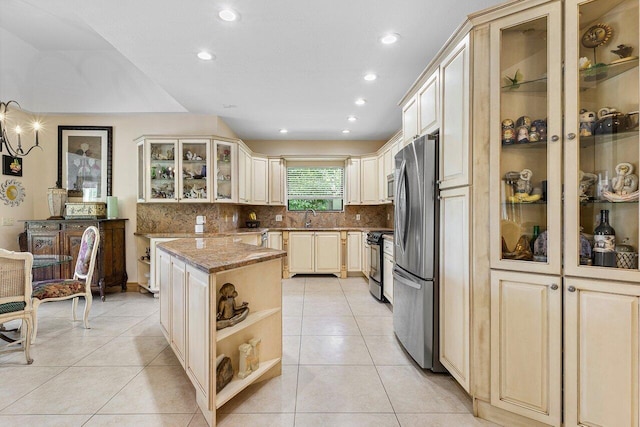 kitchen with light stone countertops, stainless steel appliances, sink, light tile patterned floors, and a kitchen island