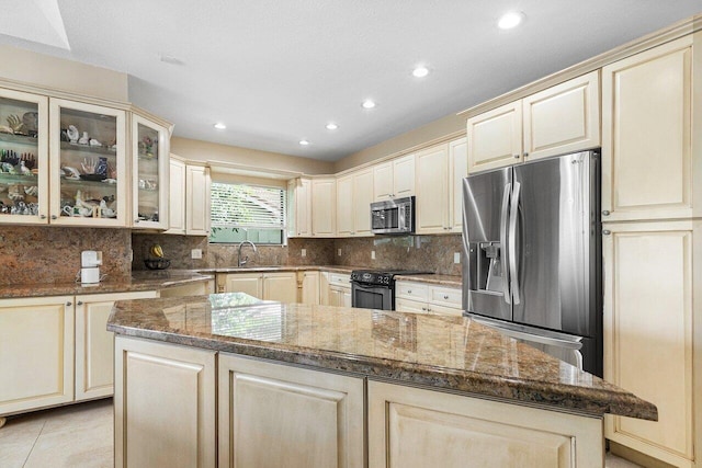 kitchen featuring dark stone countertops, sink, a center island, and appliances with stainless steel finishes