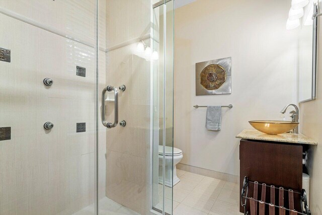 bathroom with tile patterned flooring, vanity, an enclosed shower, and toilet