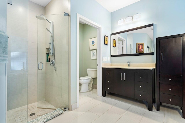 bathroom featuring tile patterned flooring, vanity, a shower with shower door, and toilet