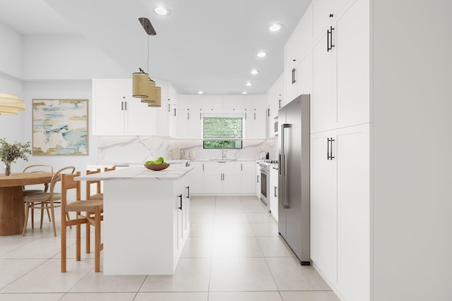 kitchen with pendant lighting, a center island, backsplash, appliances with stainless steel finishes, and white cabinetry