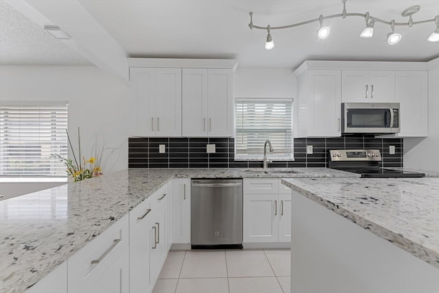 kitchen featuring white cabinetry, sink, light stone counters, appliances with stainless steel finishes, and backsplash