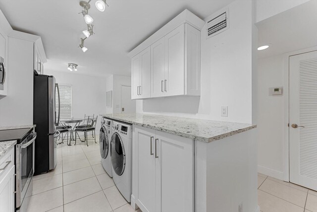 laundry room with washing machine and clothes dryer and light tile patterned floors