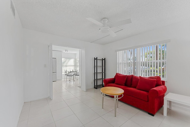 tiled living room featuring a textured ceiling, a wealth of natural light, and ceiling fan