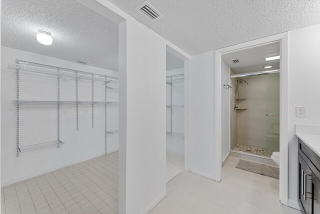 bathroom featuring a shower with door, vanity, and a textured ceiling