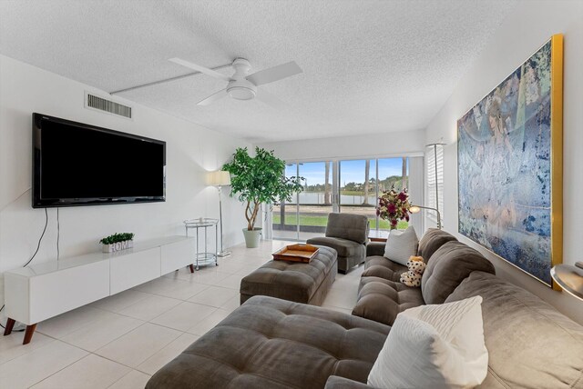 living room with light tile patterned flooring, ceiling fan, and a textured ceiling