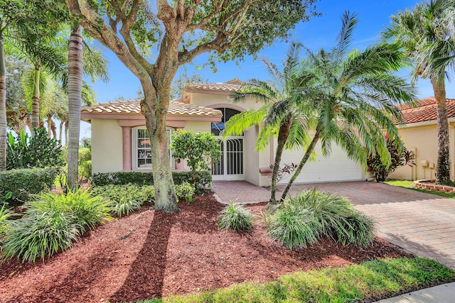 mediterranean / spanish house with driveway, stucco siding, a tiled roof, and a garage