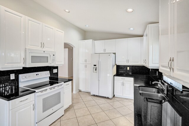 kitchen with white appliances, a sink, decorative backsplash, arched walkways, and white cabinetry