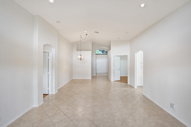 tiled spare room with lofted ceiling and a notable chandelier