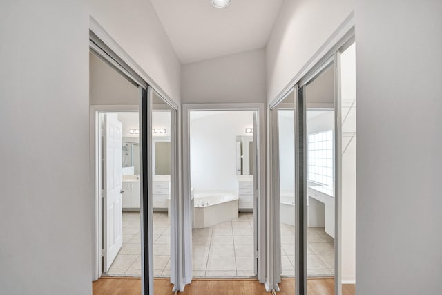 hallway with light hardwood / wood-style floors and vaulted ceiling