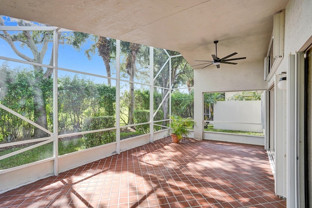 unfurnished sunroom featuring ceiling fan and a healthy amount of sunlight