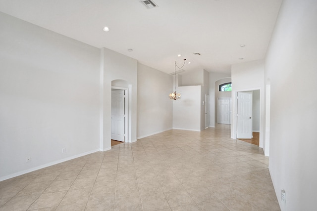 tiled spare room featuring lofted ceiling and an inviting chandelier