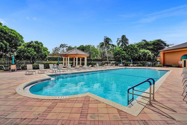 community pool with a gazebo, a patio, and fence