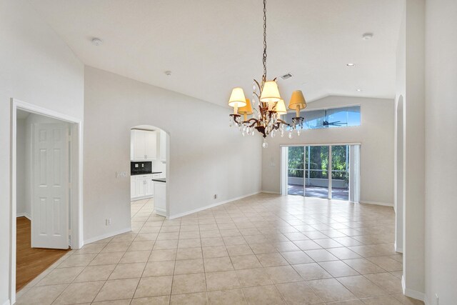 empty room with high vaulted ceiling, arched walkways, a chandelier, light tile patterned floors, and baseboards