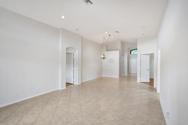 spare room featuring arched walkways, a chandelier, light tile patterned floors, high vaulted ceiling, and recessed lighting