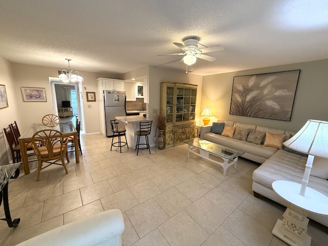 tiled living room with a textured ceiling and ceiling fan with notable chandelier