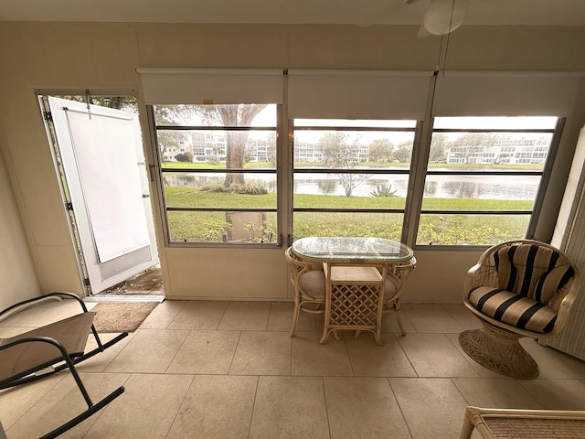 sunroom / solarium featuring ceiling fan and a water view