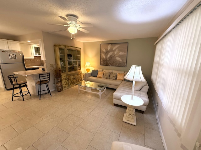 living room featuring a textured ceiling, ceiling fan, and light tile patterned flooring