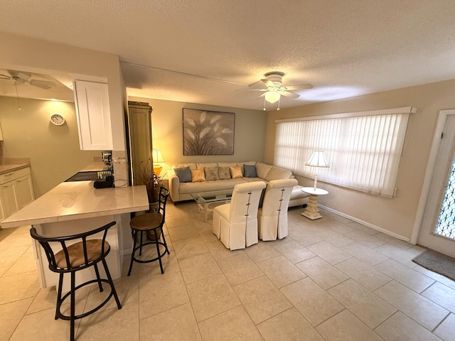 tiled living room with a textured ceiling, ceiling fan, and sink