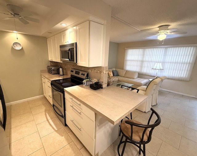 kitchen featuring stainless steel appliances, white cabinetry, light tile patterned floors, and backsplash