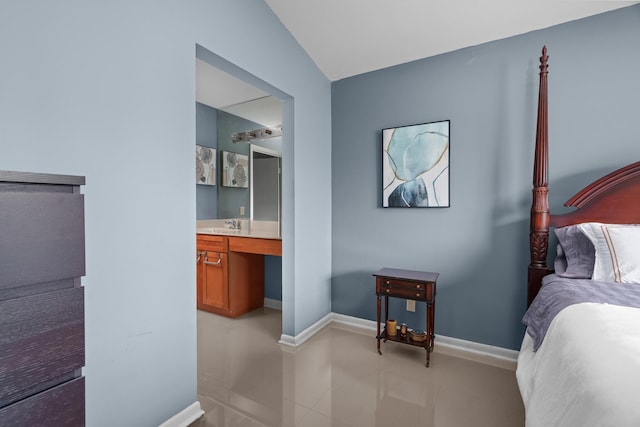 bedroom featuring vaulted ceiling, ensuite bath, and built in desk